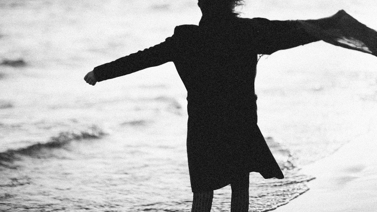 a black and white photo of a person standing on the beach